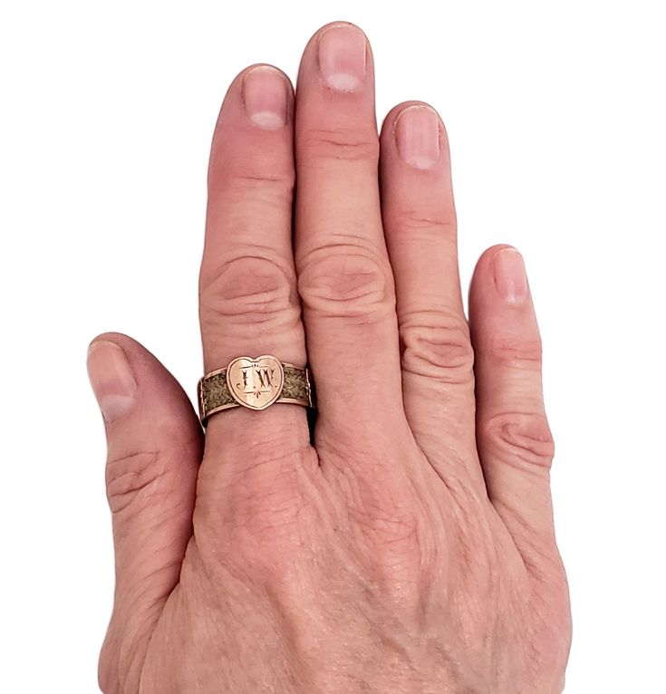 "Victorians really knew how to memorialzie their loved ones. This 9K rose gold ring is an extraordinary example of antique mourning jewelry. The initials J.W. are hand engraved in a heart shape on the front of the ring. The band is inset with meticulously plaited hair, held firmly in place with the addition of 3 decorative gold squares. A very special ring! Vintage: Late 1800s - Early 1900s Size: 7 3/4 Materials: 9K Rose Gold, Hair Marked: PB, 9c Width: 7/16\" (heart) 5/16\" (band) Stands Off Fi Heirloom Engraved Heart Ring, Victorian Rings With Engraving Option For Anniversary, Victorian Yellow Gold Initial Ring For Anniversary, Heirloom Engraved Signet Ring For Memorial, Rose Gold Initial Ring Stamped 14k, Rose Gold Stamped 14k Initial Ring, Heirloom Memorial Engraved Signet Ring, Rose Gold 14k Stamped Initial Ring, Victorian Gold Initial Ring For Anniversary