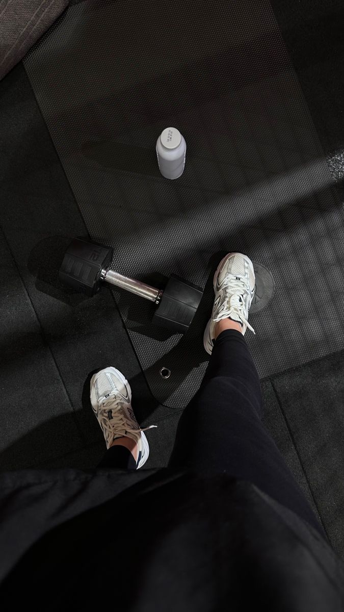 a person standing on top of a black floor next to a white cup and skateboard