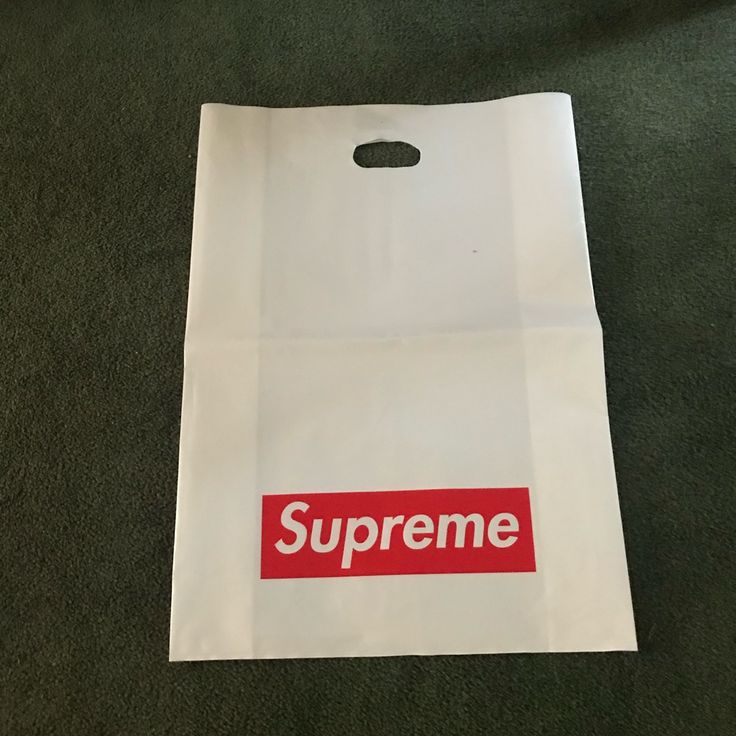 a white bag with the word supreme on it sitting on a green carpeted floor