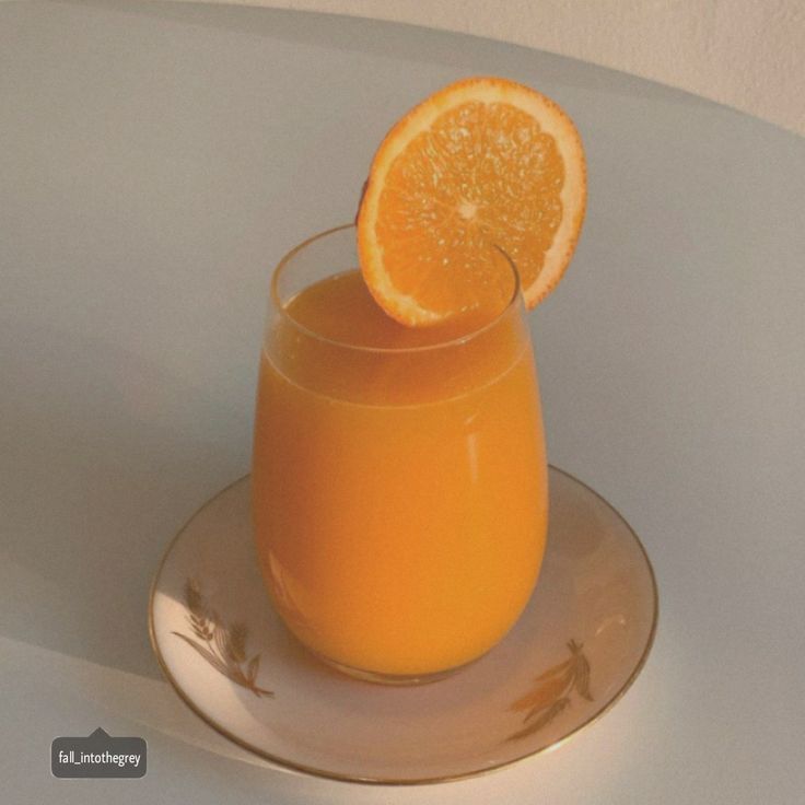 an orange juice in a glass on a plate