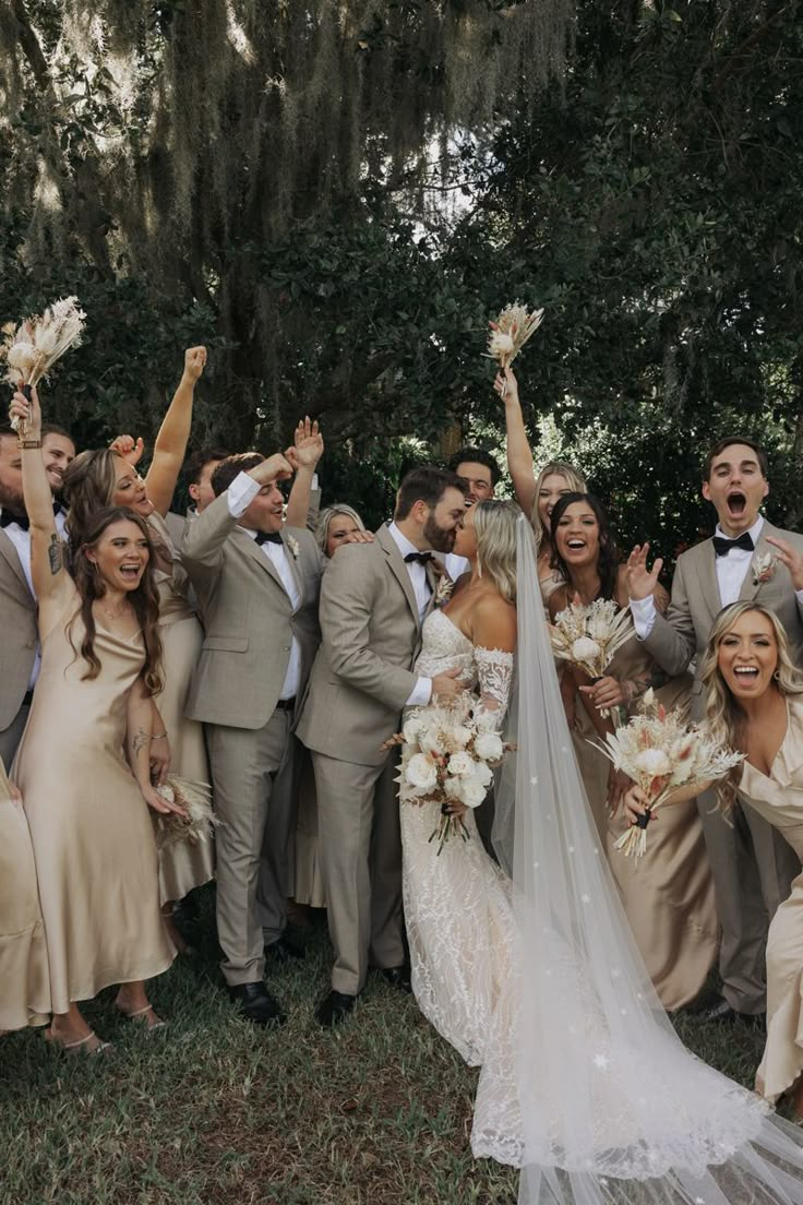 a large group of people dressed in formal wear posing for the camera with their hands up