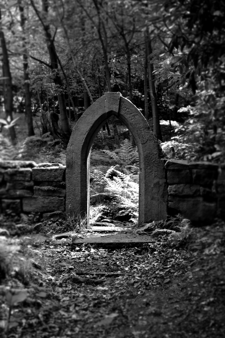 black and white photograph of an arch in the woods