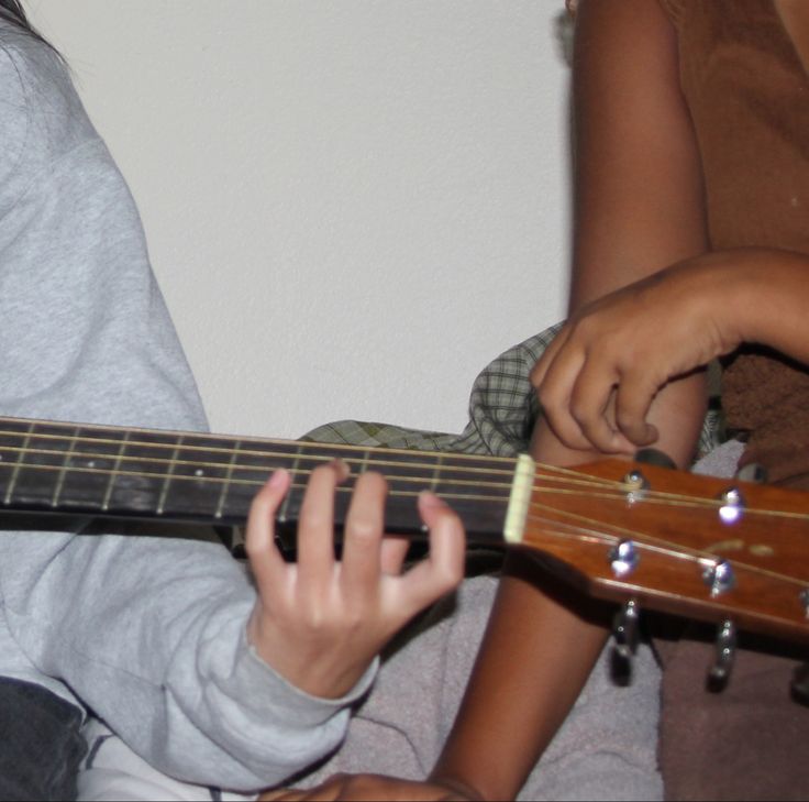 two children are playing the guitar together