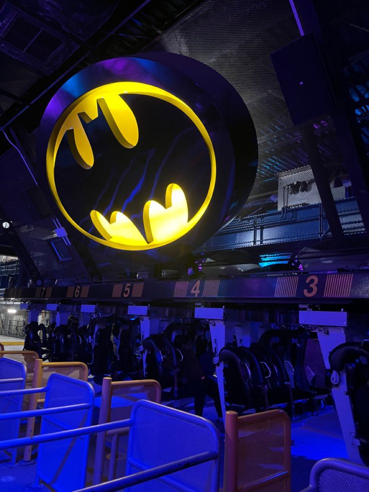 the batman logo is lit up in front of some seats at an indoor arena area