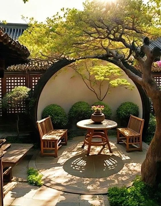 an outdoor dining area with wooden chairs and table surrounded by trees, bushes and shrubbery