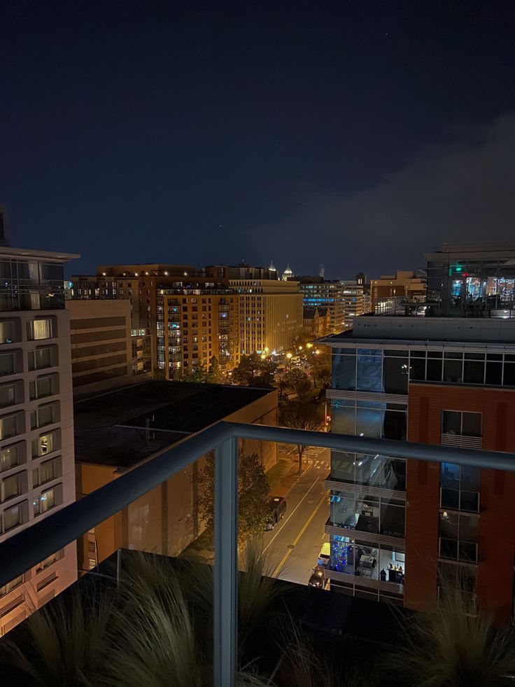 the city lights shine brightly at night from an apartment building's rooftop deck area