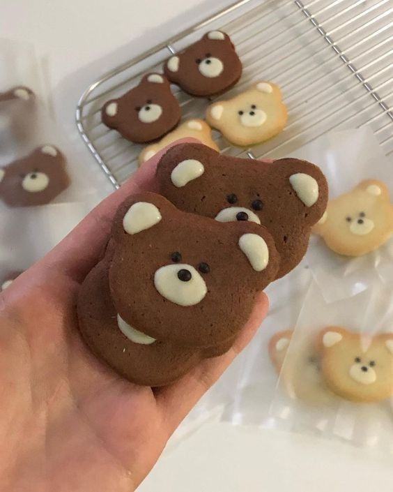 a person holding up some cookies with teddy bears on them in front of other cookies