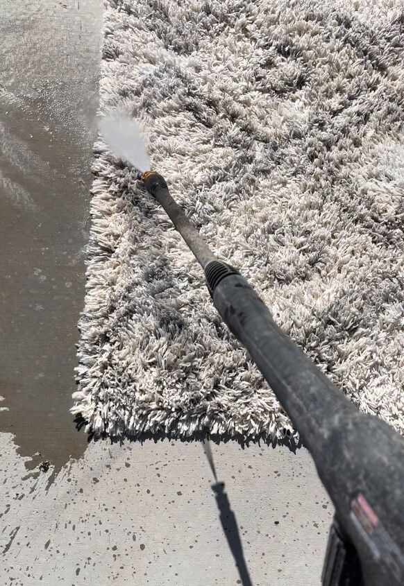 an area rug is being cleaned with a blow dryer on the ground next to it