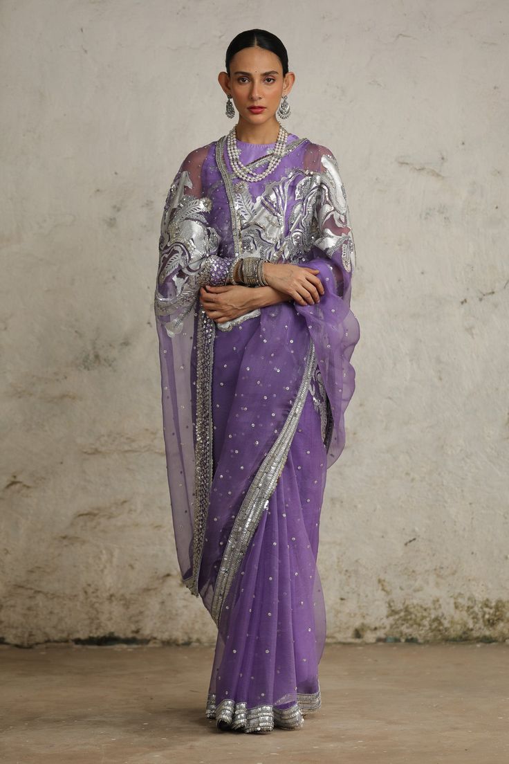 Immerse yourself in the essence of modern India and traditional Indian crafts with this exquisite sari. Crafted from luxurious silk organza, it is adorned with intricate hand embroidery using the applique and aari techniques in metallic silver. This blend of traditional craftsmanship and contemporary design makes it a true masterpiece, perfect for making a statement at any special occasion. Purple Pre-draped Saree With Zari Work For Celebration, Traditional Purple Cotton Silk Pre-draped Saree, Designer Wear Organza Blouse Piece For Transitional Season, Transitional Organza Blouse Piece For Designer Wear, Festive Organza Blouse Piece For Transitional Season, Festive Transitional Organza Blouse Piece, Transitional Anarkali Pre-draped Organza Saree, Purple Organza Pre-draped Saree With Dupatta, Designer Wear Pre-draped Organza Saree For Eid