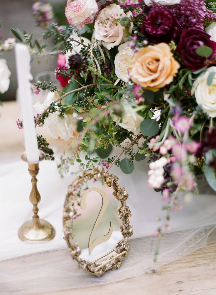 an arrangement of flowers and candles on a table with a heart shaped mirror in the middle