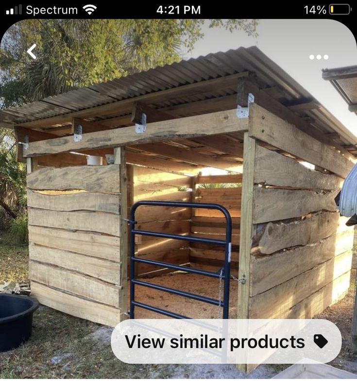 an outhouse made from pallets and wood with metal bars on the roof, next to a trash can