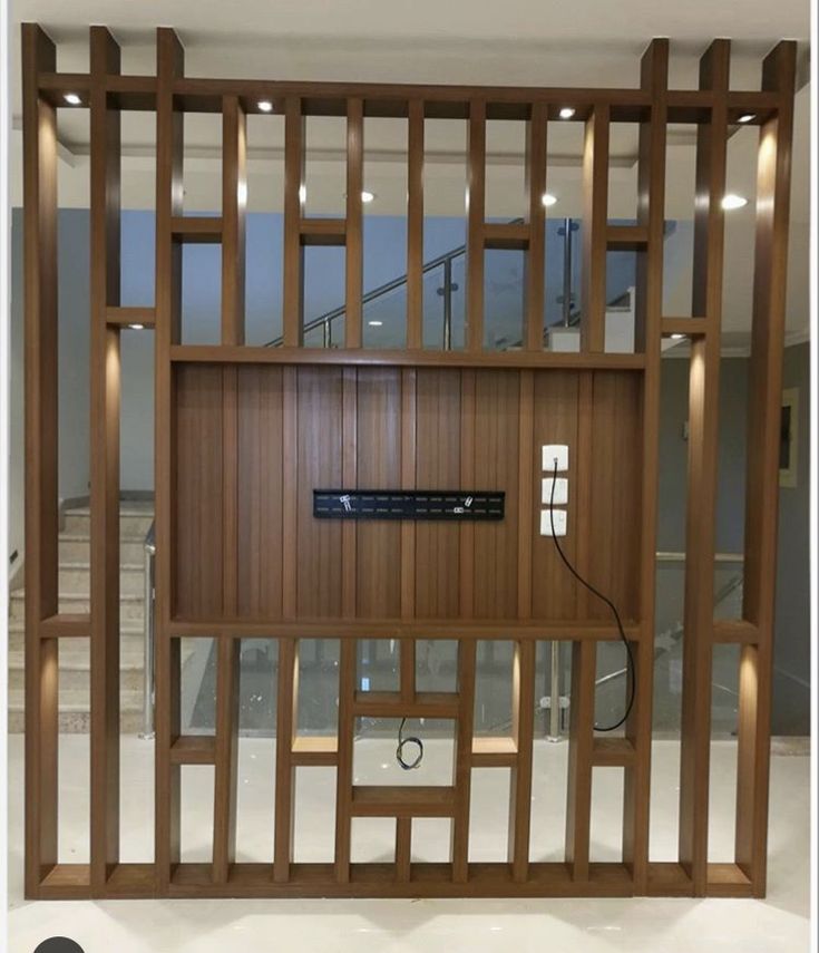 a large wooden paneled room divider with an electronic device on the wall in front of it