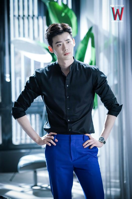 a young man in blue pants and black shirt standing with his hands on his hips