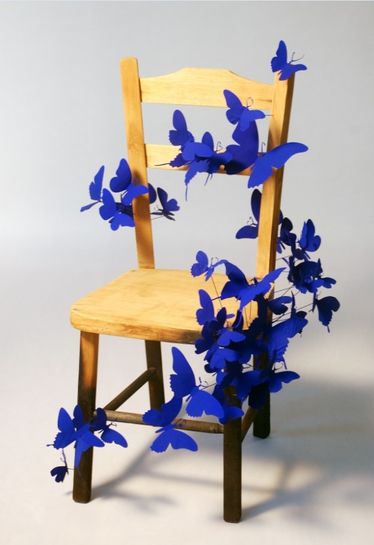 a wooden chair with blue butterflies attached to it's back and seat, against a white background