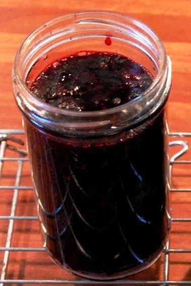 a glass jar filled with black liquid sitting on top of a metal rack next to a wooden table