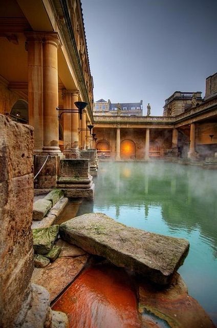 a large body of water surrounded by stone pillars and columns in front of a building