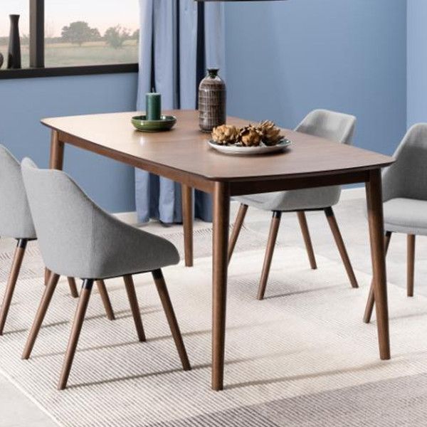 a dining table with four chairs and a plate of food on it in front of a window