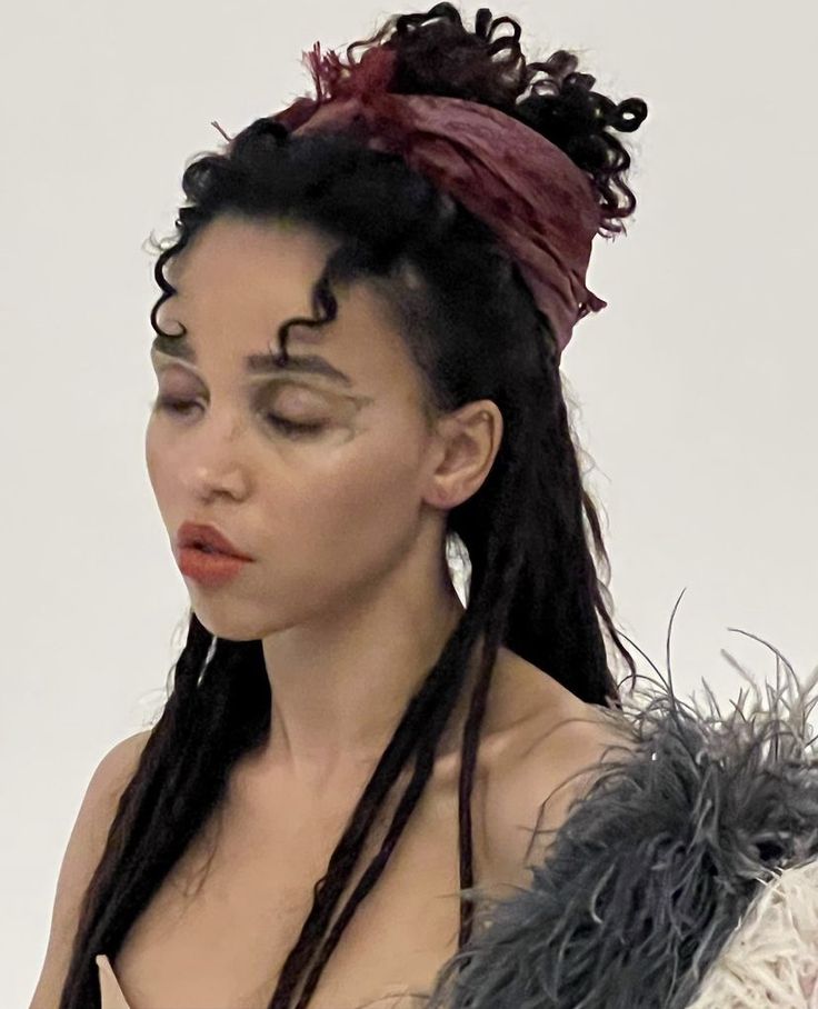 a woman with dreadlocks is looking at her cell phone while wearing a feathered headband