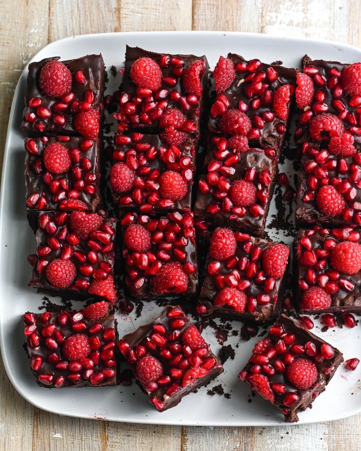 chocolate brownies with raspberries and chocolate frosting on a white platter