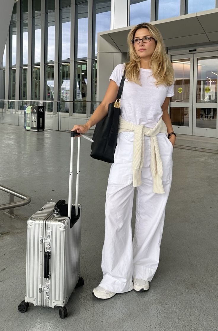 a woman is standing with her luggage at the airport