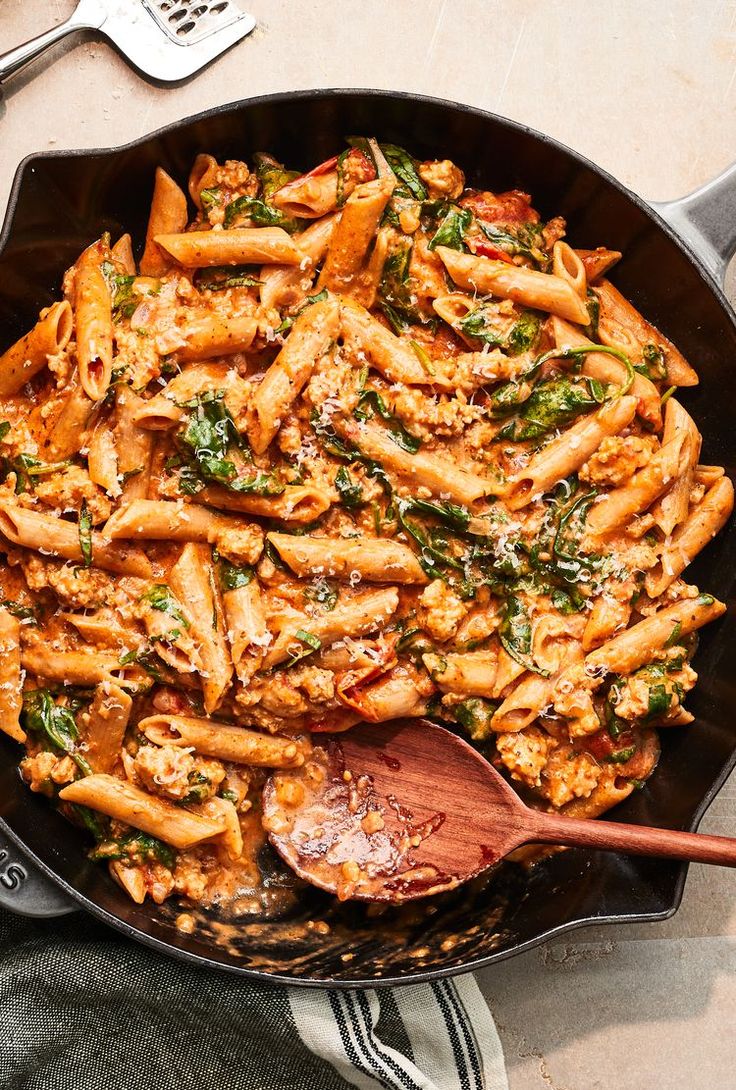 a skillet filled with pasta and spinach