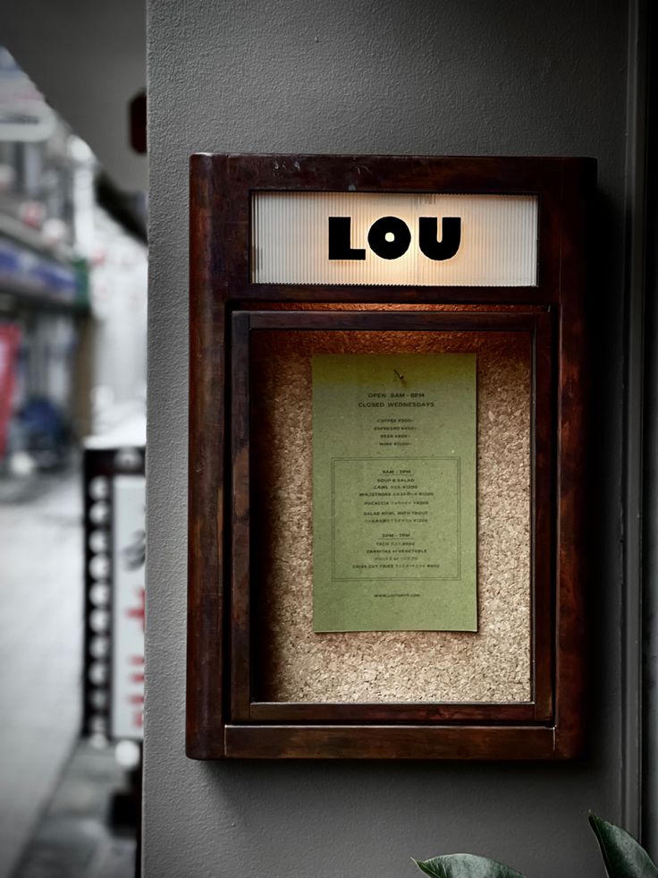 a wooden frame with a lit up sign above it and a plant next to it