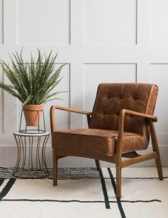 a brown chair sitting next to a potted plant on top of a white rug