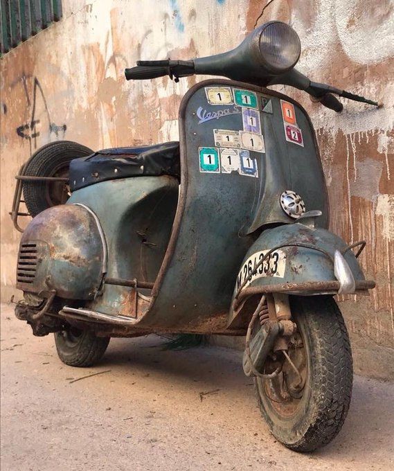 an old scooter is parked in front of a wall