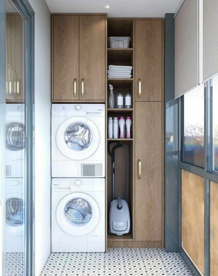 a washer and dryer in a small room with wooden cupboards on the wall