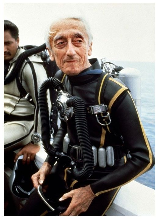 an older man in scuba gear sitting on a boat with another man standing behind him