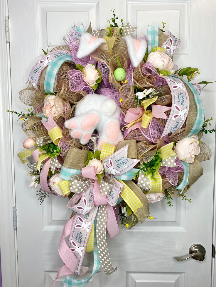 a wreath on the front door decorated with pink, white and blue ribbons for easter