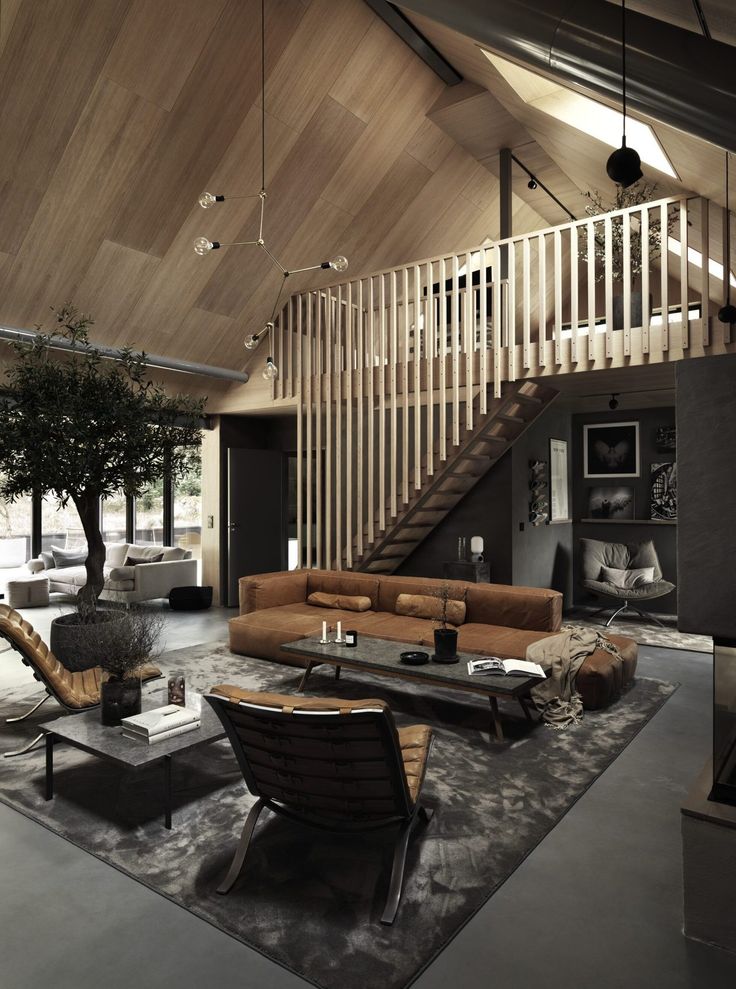 a living room filled with lots of furniture and a wooden staircase leading up to the second floor