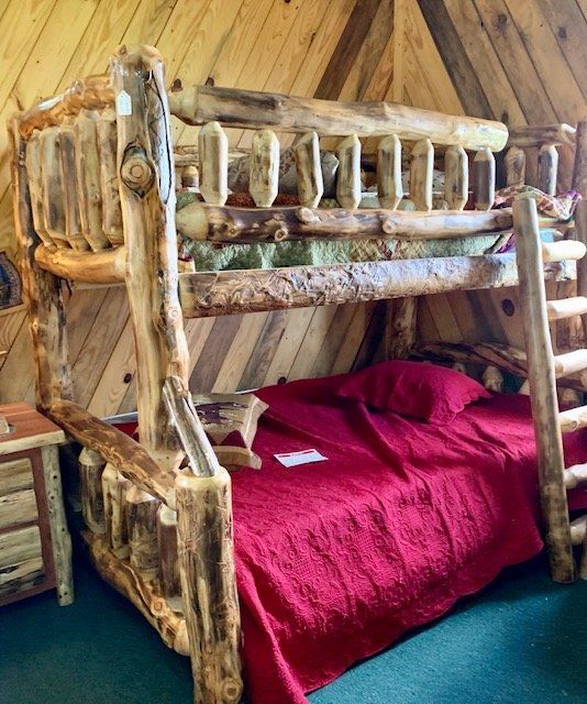 a wooden bunk bed sitting inside of a bedroom next to a red bedspread