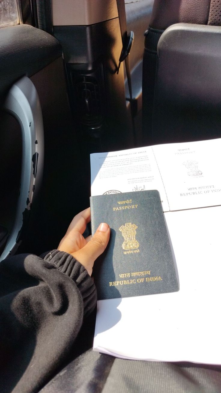 a person is holding a passport in their hand while sitting in the back seat of a car