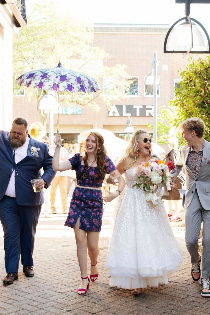 the bride and groom are walking down the street with their arms in the air as they hold an umbrella