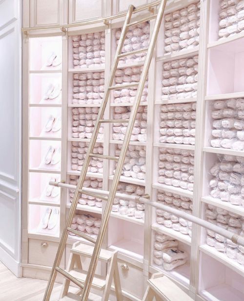 a room filled with lots of white shelves covered in stacks of shoes and ladders