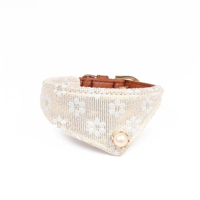 a white dog collar with pearls on it's side and a brown leather buckle