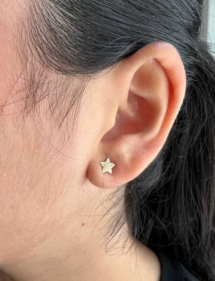 a close up of a person's ear with a small gold star on it