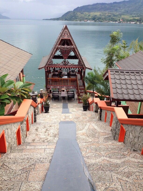 a walkway leading up to a building with an open roof and water in the background