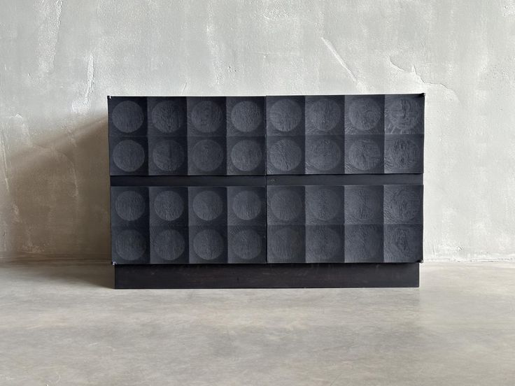 a black box with circles on it sitting in front of a concrete wall and floor