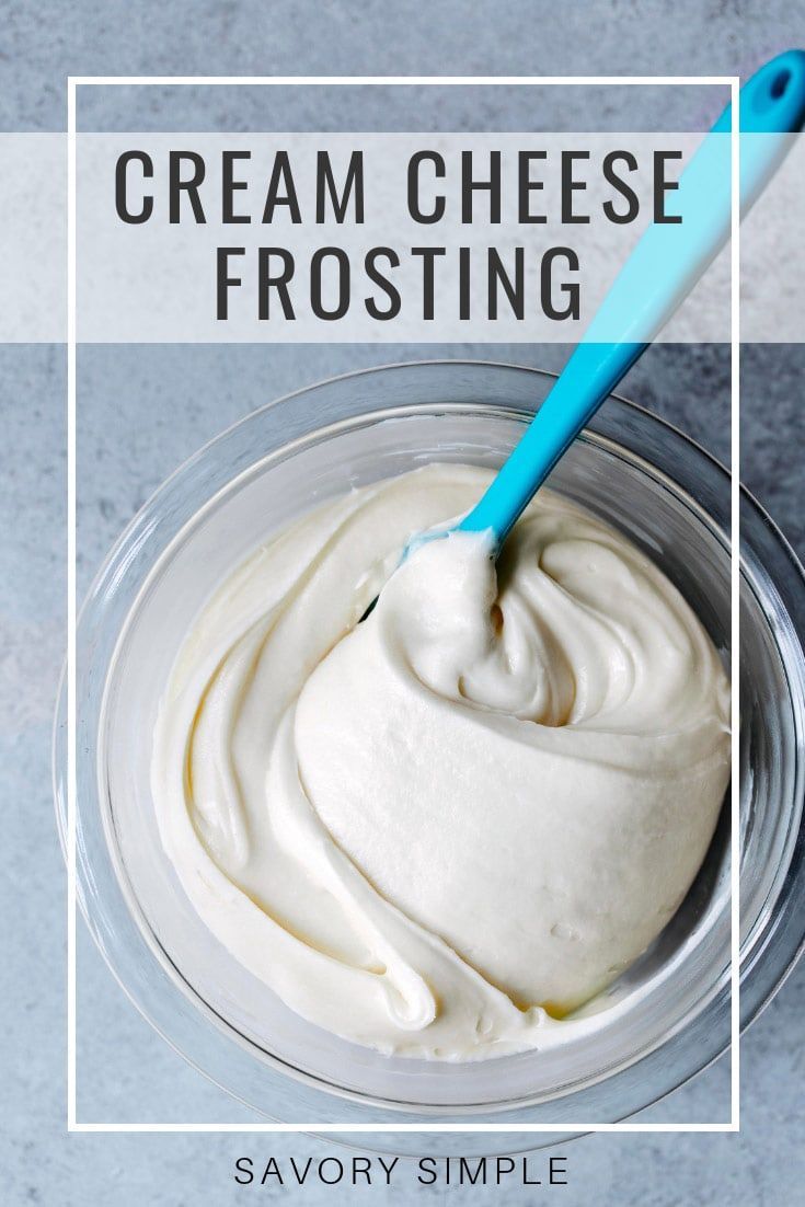 cream cheese frosting in a glass bowl with a blue spoon