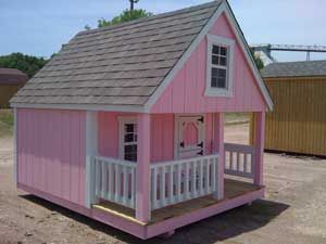 a little pink house sitting on top of a dirt field