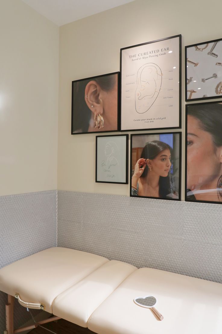 a white bench in front of pictures on the wall with earring hooks attached to it