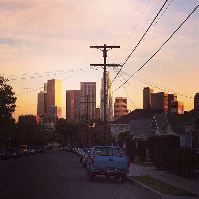 cars are parked on the street in front of some buildings and power lines at sunset