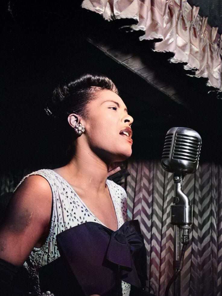 a black and white photo of a woman singing into a microphone