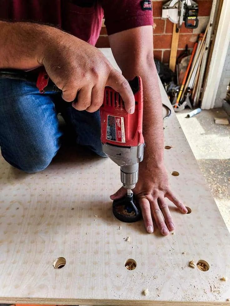 a man is using a drill to attach screws on a piece of plywood