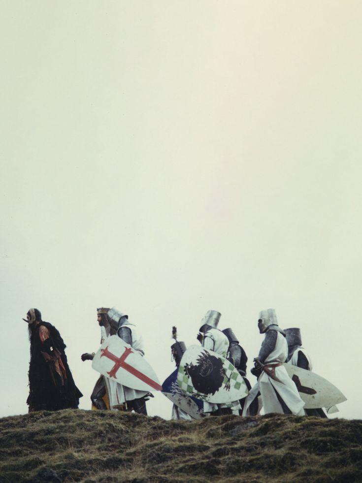 four people dressed in knight costumes standing on top of a hill