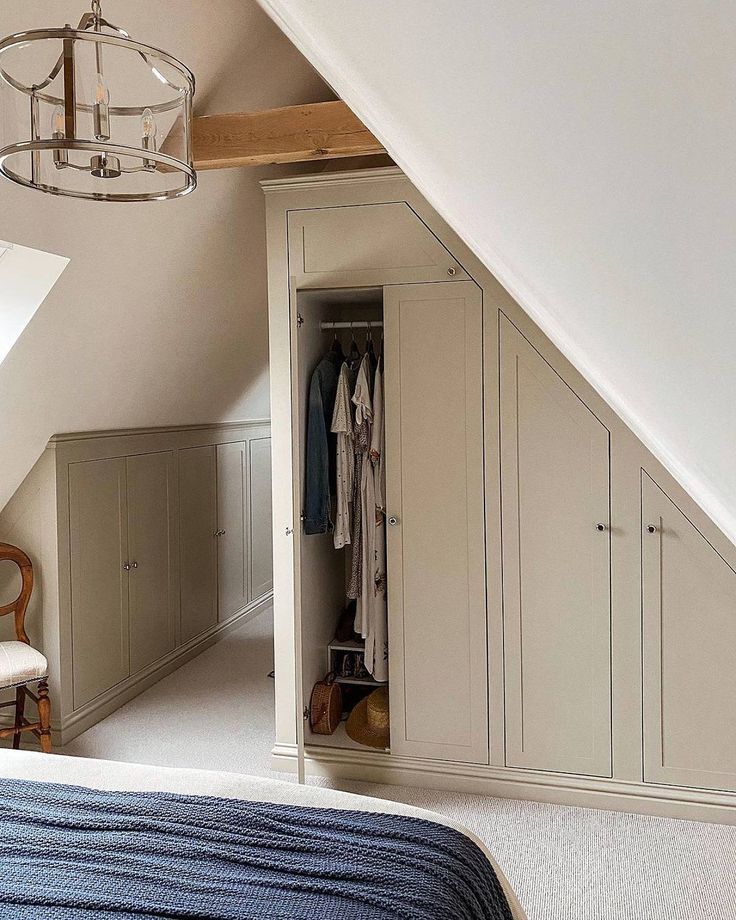 an attic bedroom with white walls and carpeted flooring, built in closets