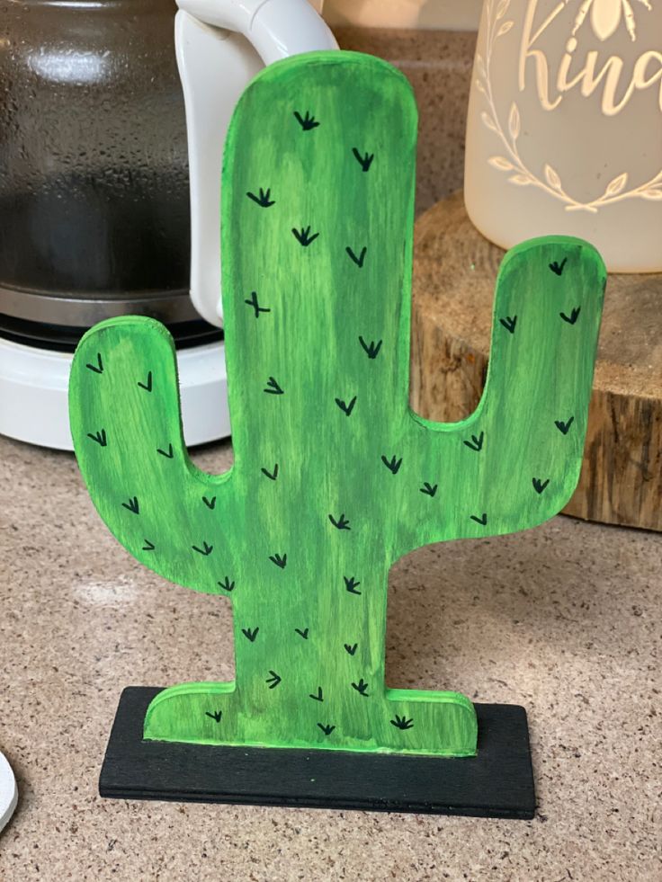 a green cactus sitting on top of a counter next to a coffee pot and kettle