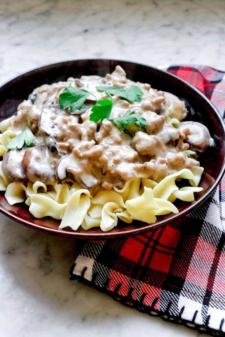 a bowl filled with pasta covered in gravy and garnished with parsley